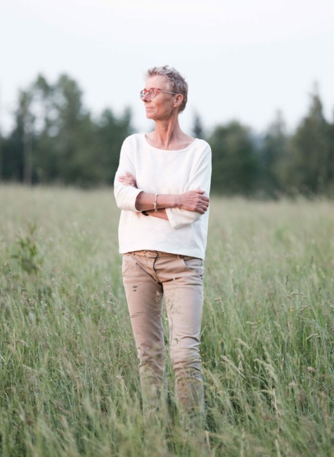 Helga Honeder steht in einem Feld im Mühlviertel und lässt dabei den Blick über die Landschaft streifen.